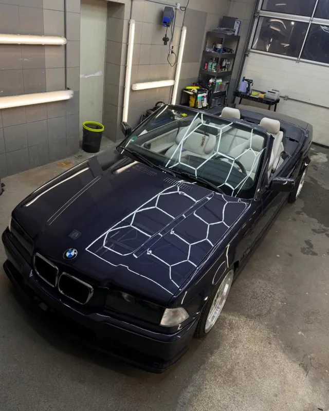 Dunkelblaues BMW E36 Cabrio in der Halle mit Wabenspiegelung auf der Motorhaube