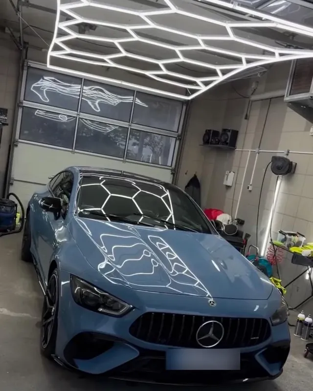 Hellblauer Mercedes-AMG GT 63 S in der Halle, das Wabenlicht spiegelt sich in der Motorhaube