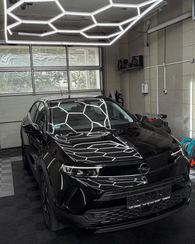 Schwarzer Opel Mokka in der Halle, Wabenlicht spiegelt sich auf der Motorhaube