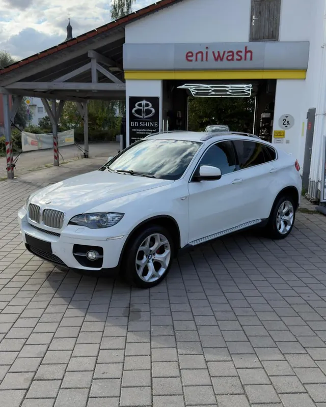 Weißer BMW X6 vor der Halle